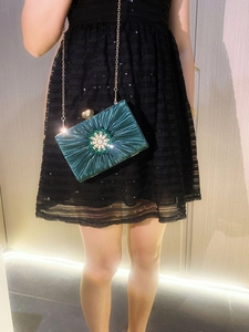 Detail of green pleated satin evening bag with sparkling floral rhinestone buckle