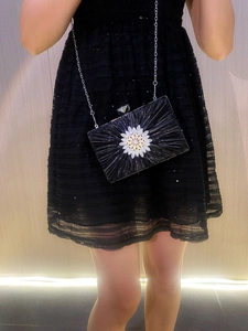 Detail of black pleated evening clutch with crystal flower and silver chain strap