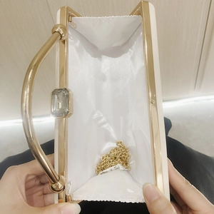 Macro view of white satin wedding clutch interior with gold metal handle and chain