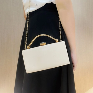 Detail of cream rectangular evening clutch with wavy texture and gold metal handle