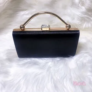 Close-up of black evening clutch with vertical textures and gold crystal handle