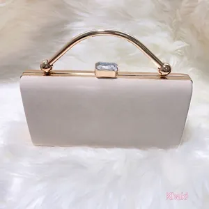 Khaki evening clutch bag with golden circular handle on white faux fur background