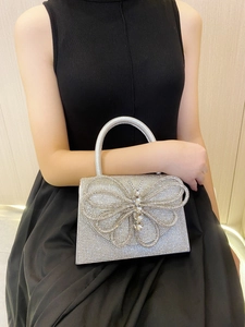 Close-up of sparkling silver rhinestone evening bag featuring a large crystal bow accent