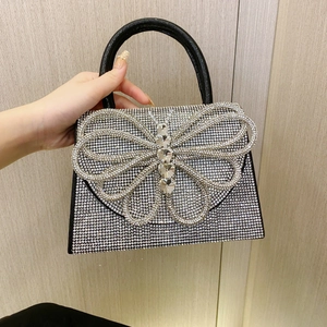 Detail of a black evening bag with silver rhinestones and a large crystal butterfly charm