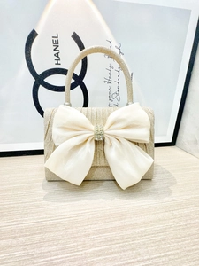 Detail of champagne gold evening bag featuring oversized organza bow and rhinestone buckle