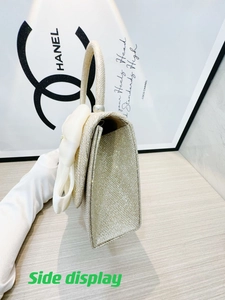 Side view of golden glitter handbag featuring an elegant cream bow and pearl detail