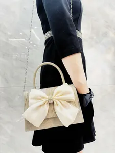 Detail of champagne glitter evening bag with beige satin bow and rhinestone decoration