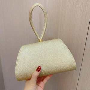 Close-up of champagne gold glitter evening bag with round handle and spherical metal hardware