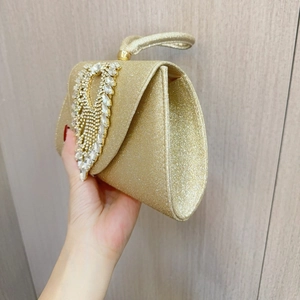 Macro detail of luxury gold evening bag featuring sparkling heart-shaped rhinestone patterns