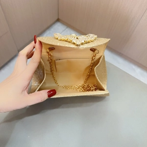 Detailed interior of golden evening clutch featuring rhinestone bow and metal chain strap