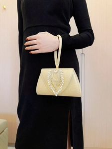 Detailed view of sparkling rhinestones and woven handle on a gold evening clutch bag