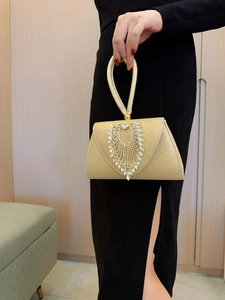 Detail of gold evening bag with V-shaped rhinestone tassels and crystal handle