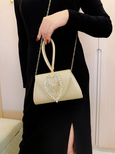Detailed close-up of sparkling gold evening bag with rhinestones and metal chain strap