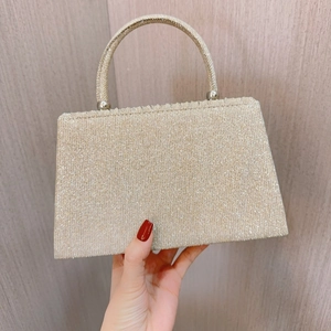 Detail der goldenen Abendtasche mit Glitzerfalten und rundem Metallgriff