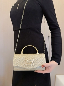 Goldene Pailletten-Abendtasche mit Perlenschnalle und Bambusgriff auf einem schwarzen Kleid