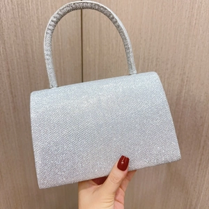 Detail view of a silver sequin evening bag with a metallic handle and glitter texture