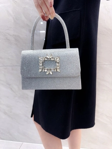 Close-up of sparkling silver sequin handbag featuring a large crystal rhinestone buckle