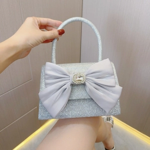 Detail view of a silver sequin evening bag with large satin bow and crystal buckle