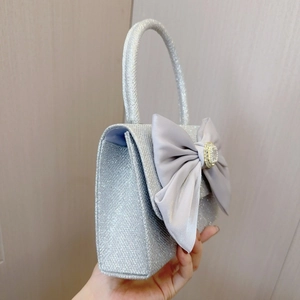 Close-up of a silver sequin evening bag with a large silk bow and crystal buckle detail
