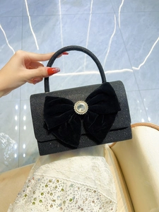 Detail of black glitter evening bag with large velvet bow and crystal brooch
