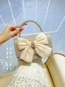 Detail of champagne gold sequin handbag with satin bow and crystal buckle detail