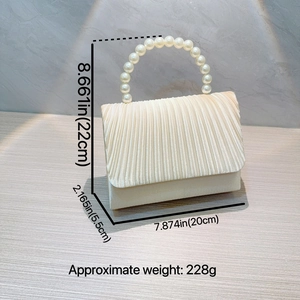 Detailed view of cream pleated evening bag with pearl handle and dimension markings