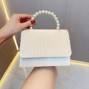 Detail of pleated satin evening bag with oversized pearl handle for wedding party