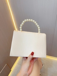 Detail of elegant pleated satin evening bag with a luxury faux pearl beaded handle