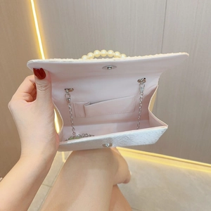 Detail of evening bag showing pearl handle, silver chain and pink silk interior lining