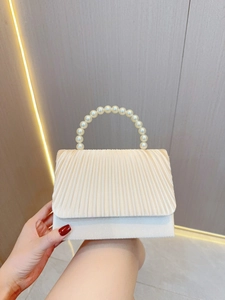 Detailed view of cream pleated evening bag with elegant large pearl handle for weddings
