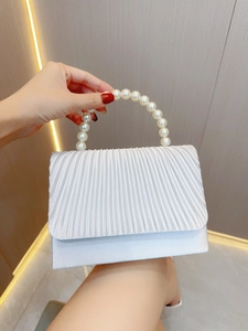 Detail of pleated pearl white evening bag featuring a decorative large pearl handle