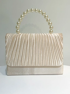 Detailed view of champagne pleated evening bag with elegant large faux pearl handle