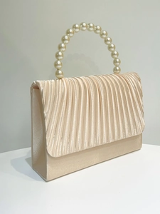 Detail of champagne satin evening clutch featuring pleated flap and pearl handle