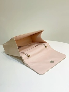 Detail view of champagne pleated evening bag interior with metal chain and magnetic clasp