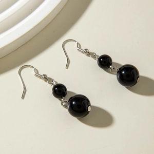 Close-up of black acrylic beaded drop earrings with silver hooks on white background