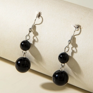 Detail shot of black beaded drop earrings with silver hooks on a cylindrical display stand