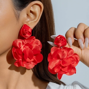Gros plan de grandes boucles d'oreilles roses en tissu rouge avec texture en soie