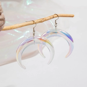 Close-up of holographic resin crescent moon earrings hanging on a natural wooden branch