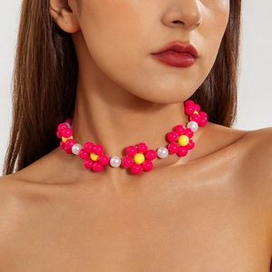 Detailaufnahme einer rosa-gelben Blumen-Perlenkette mit weißen Perlen am Model getragen
