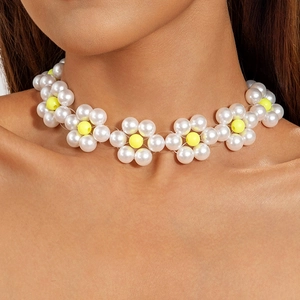 Detailansicht einer Gänseblümchen-Perlenkette mit weißen Perlen und gelben Blütenakzenten