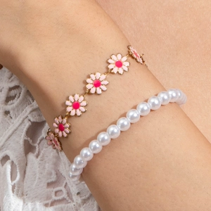 Detail of floral daisy chain and white faux pearl beads on a feminine layered bracelet set