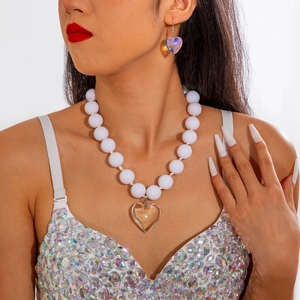 Parure de bijoux exagérée avec perles blanches et pendentifs cœur sur un mannequin