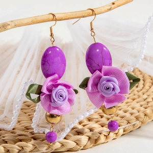Detail of bohemian drop earrings with turquoise stone and purple silk ribbon flowers