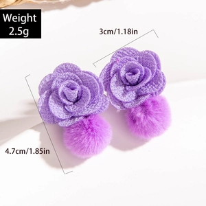 Detail view of purple floral earrings with plush pom poms and beaded flower design