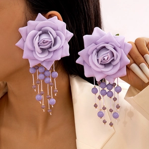 Detail of purple fabric rose earrings with dangling beaded tassels on a model
