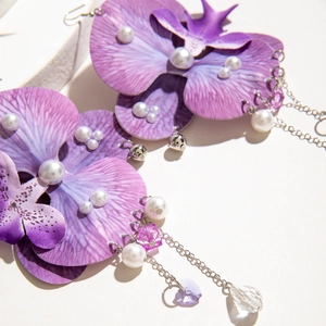 Detailed macro view of purple silk flower earrings with white pearls and crystal pendants
