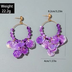 Detail view of bohemian hoop earrings with purple flower petals and bead tassels