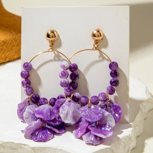 Detailed close-up of purple petal tassel earrings with gold metal rings and marble beads