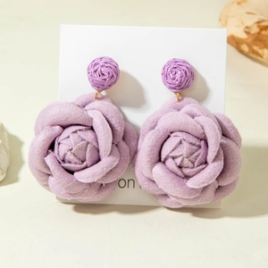 Detail of purple fabric rose earrings with woven beads and layered petal texture