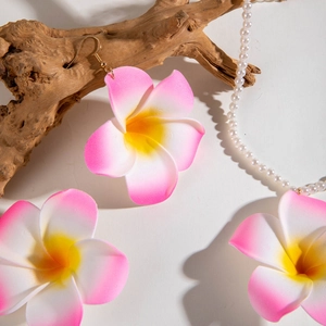 Détail de boucles d'oreilles frangipanier roses et blanches sur perles blanches